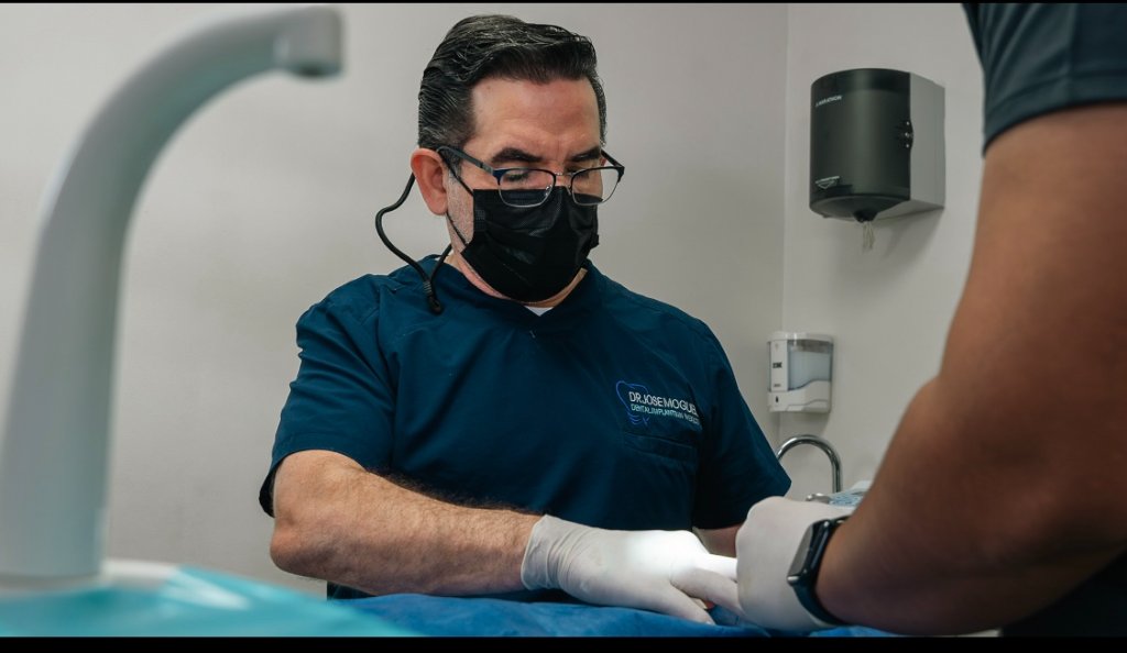 Dr. Moguel preparing for dental procedure with protective equipment